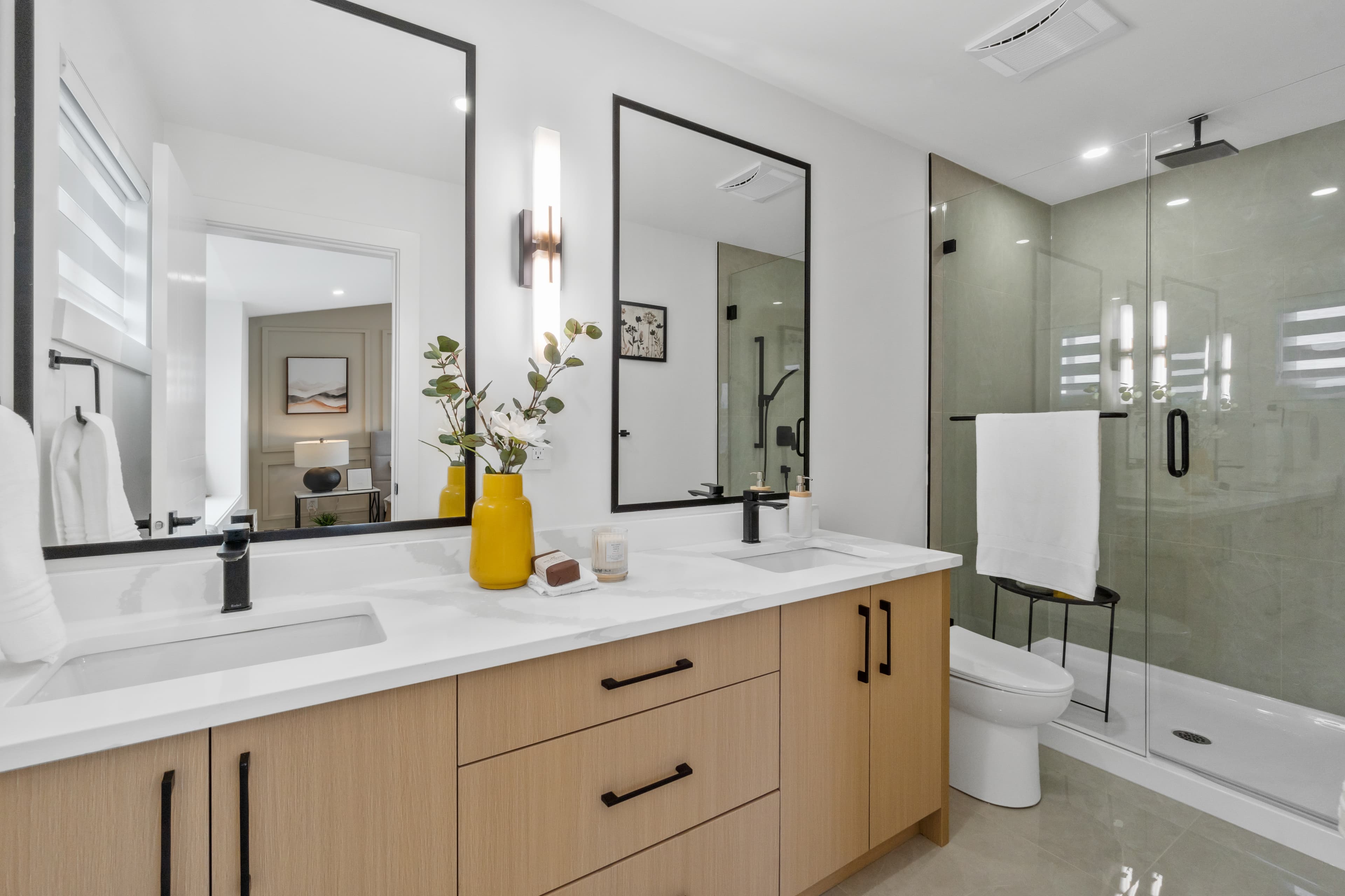 Bathroom at Willoughby Row with double vanity, black-framed mirrors, and glass shower