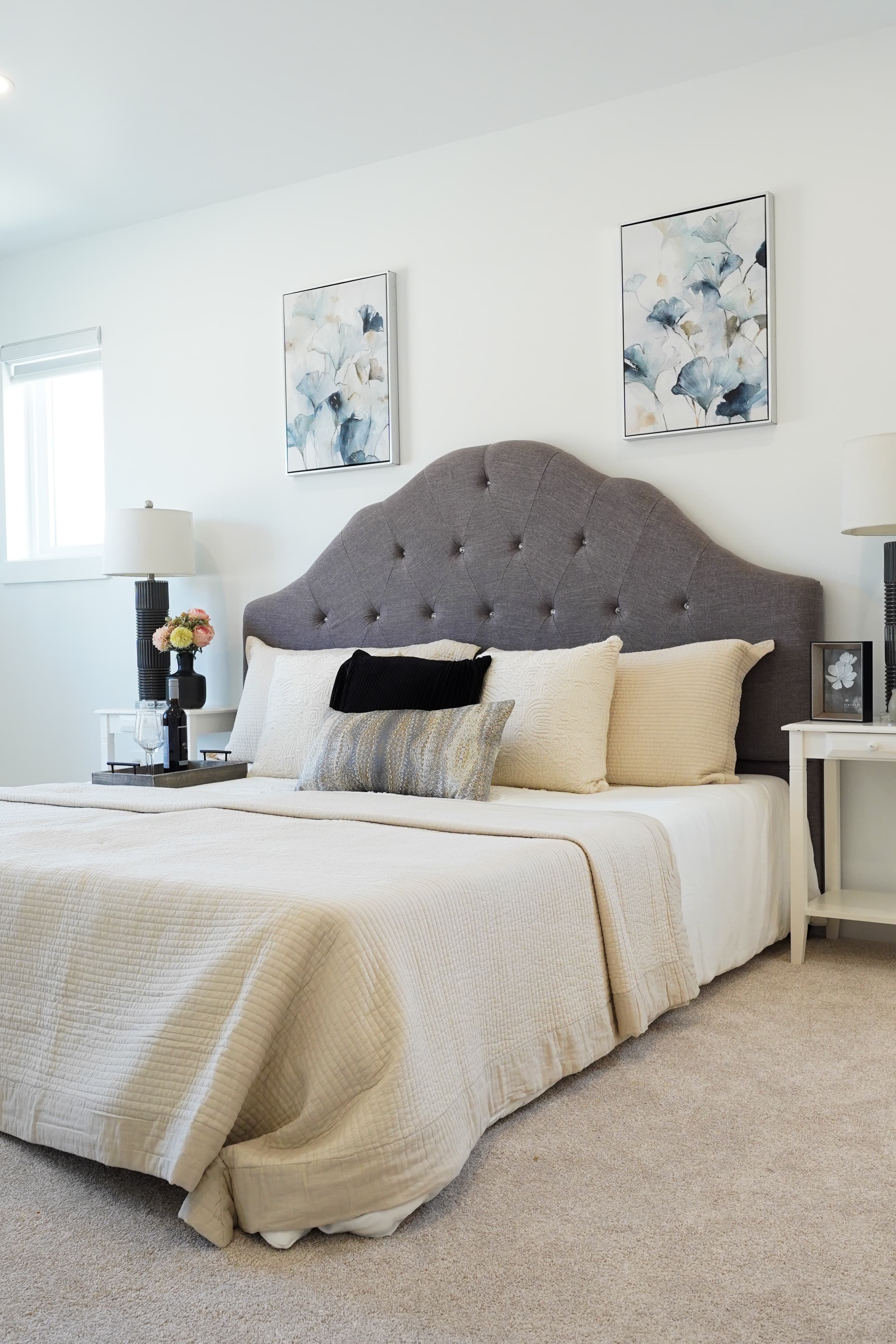 Primary bedroom headboard at Willoughby Row with tufted upholstery and framed botanical prints