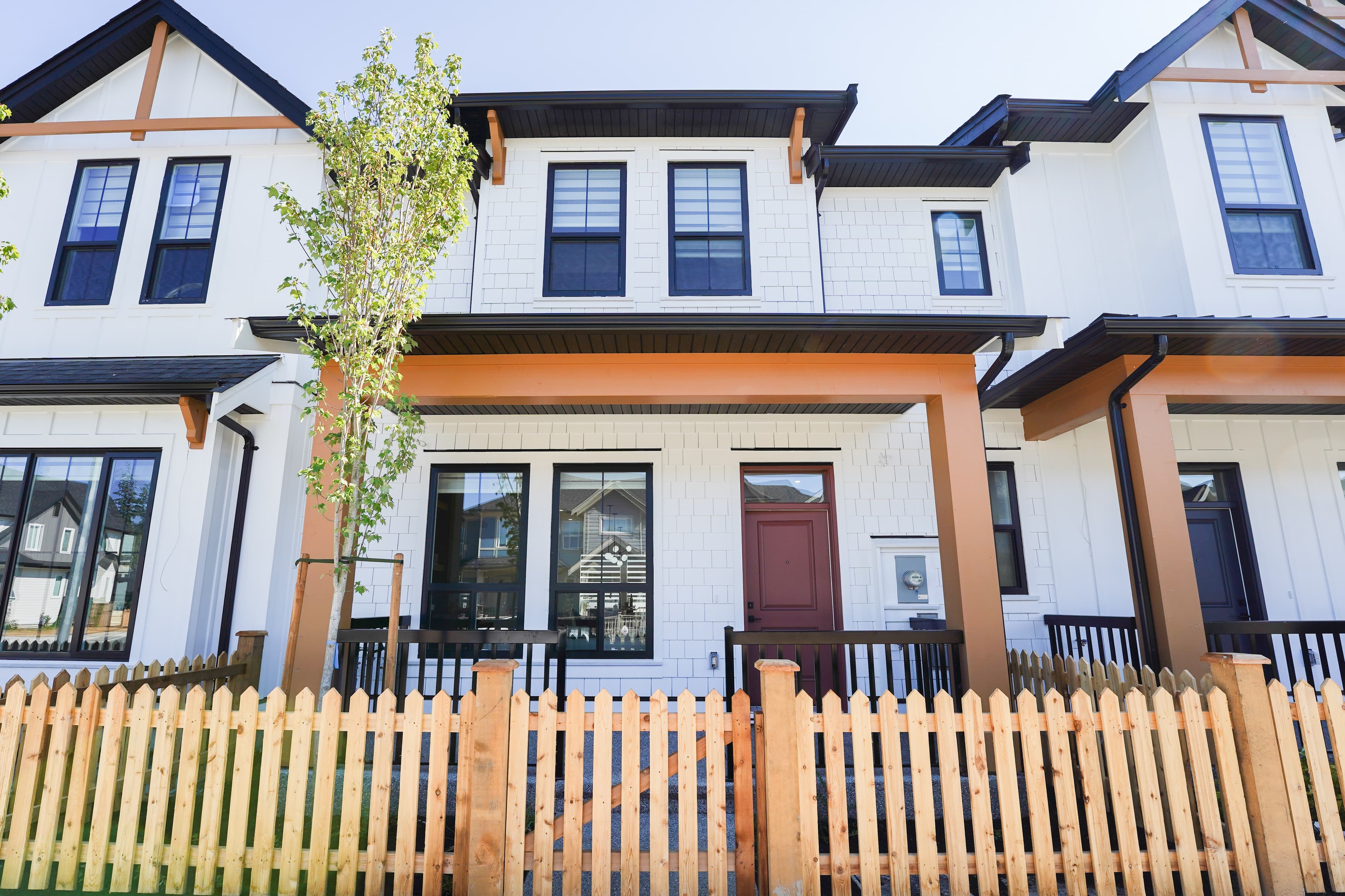 Front elevation of a pair of Willoughby Row homes with rust-toned trim and a red front door